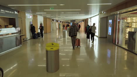 Siguiendo-A-Los-Pasajeros-En-El-Interior-Del-Aeropuerto-De-Orly-En-Su-Camino-Hacia-El-Embarque-Y-El-Paso-Frente-A-Las-Tiendas-Libres-De-Impuestos