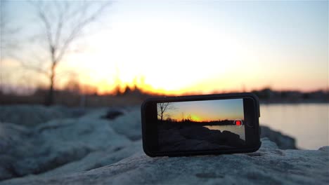 Ein-IPhone-Auf-Einem-Felsen,-Das-Eine-Zeitrafferaufnahme-Des-Sonnenuntergangs-Aufzeichnet