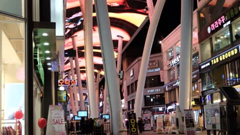 A-view-of-a-shopping-street-with-lights,-banners,-and-advertisements-all-over-the-place-at-night