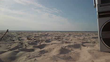 Retro-old-boombox-music-player-lays-on-a-beach-on-a-sunny-day-near-the-sea