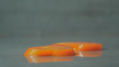 Fallende-Scheibe-Tomate-über-Andere-Scheiben,-Nassen-Hintergrund