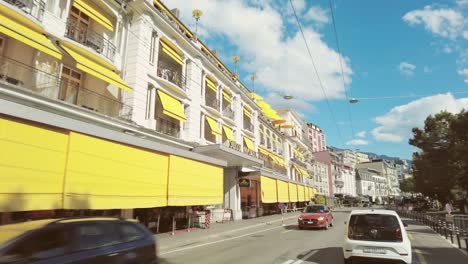 Sunny-day-car-drive-through-vibrant-city-streets-towards-Lavaux-vineyards