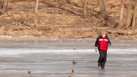 A-slow-motion-shot-of-a-young-boy-wearing-a-bear-hat-running-on-ice