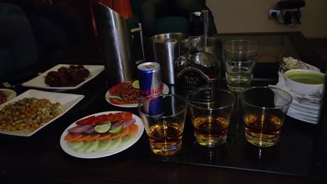 Bartender-putting-ice-cubes-in-alcohol-and-setting-up-snacks-for-friends-at-a-pub-bar-at-night