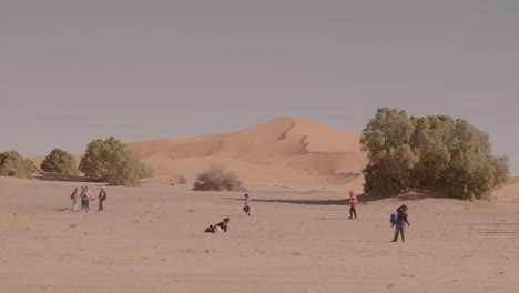 Children-play-in-the-sand-near-the-Sahara-desert-in-Merzouga,-Morocco