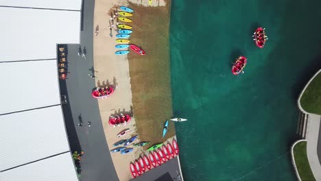 Toma-Aérea-De-Vista-De-Pájaro-Con-Drones,-De-Un-Grupo-De-Personas-Practicando-Deportes-Acuáticos,-Rafting,-Kayak,-En-Un-Parque-Acuático