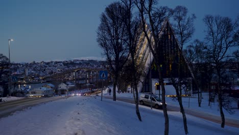 Coches-Pasando-Por-La-Catedral-ártica-De-Tromso-En-La-Brillante-Noche-Nevada