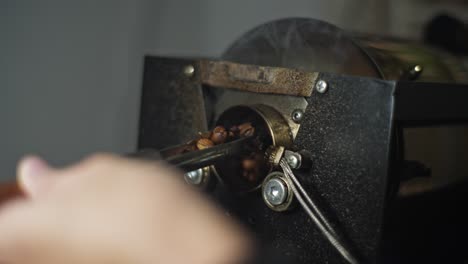 Person-checking-the-roasting-level-of-the-coffee-beans-from-machine