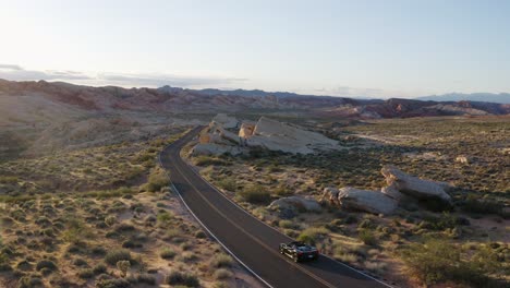 Ferrari-convertible-driving-through-the-Valley-of-Fire-in-Nevada,-USA,-at-sunset