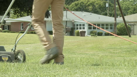 Man-mowing-grass-in-residential-neighborhood-with-house-in-background