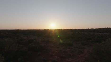 Panning-drone-clip-of-bright-sunrise-over-Australian-outback,-with-unique-lens-flares