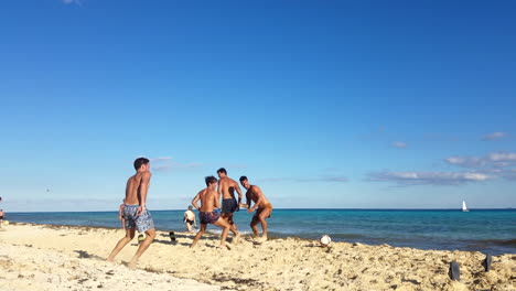 Hombres-En-Forma-Jugando-Al-Fútbol-En-La-Playa-En-México.