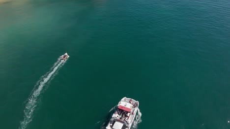 Catamaran-cruise-with-tourists-on-a-green-blue-ocean-with-speed-boat-alongside