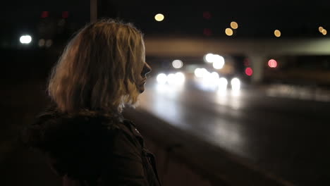 A-girl-stands-by-a-highway-at-night