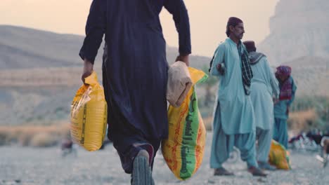 Hardworking-Pakistani-man-carrying-food-item-packets-for-food-Distribution-to-Poor-People-of-Balochistan,-Pakistan