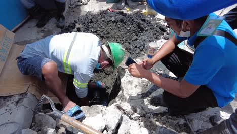 Foremen-wearing-safety-reflective-vests-used-their-shovel,-mixed-cement,-and-demolition-hammer-to-perform-excavation-beside-the-road-gutter-to-install-new-water-piping-from-the-main-water-line