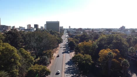 A-push-up-drone-shot-of-a-wide-road-surrounded-by-trees-under-sunny-conditions