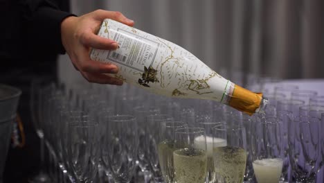 Hand-of-man-pouring-champagne-into-many-glasses
