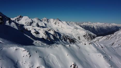 Snow-covered-Alpine-mountains-in-Europe,-aerial