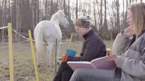 Female-participants-of-equine-assisted-therapy-workshop-take-notes-in-journal