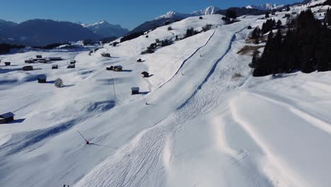 Quiet-ski-piste-on-sunny-day-in-Alpine-valley-with-white-snow,-aerial