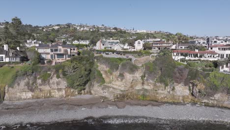 Aerial-pull-back-of-houses-on-an-oceanside-cliff-in-San-Diego,-California-on-a-bright-sunny-day