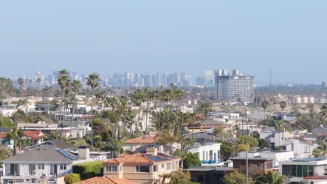 Aerial-track-back-of-a-neighborhood-in-San-Diego,-California-with-city-skyline-in-the-background-on-a-sunny-day