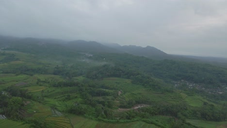 Stormy-clouds-and-fog-flowing-over-Indonesia-landscape,-aerial-view