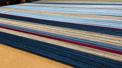 Yarn-fibers-for-mat-with-shades-of-blue-and-red-on-table,-detailed-pan