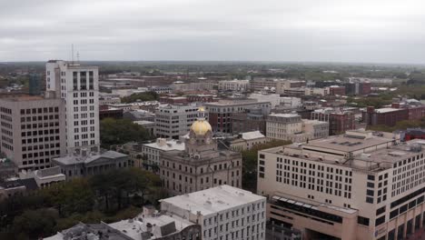 Low-close-up-aerial-shot-of-the-historic-City-Hall-building-along-the-river-in-downtown-Savannah,-Georgia