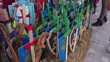 Slow-motion-shot-of-a-group-of-children's-war-toys-made-of-wood-at-a-fair-in-Huelva,-Spain-during-the-morning