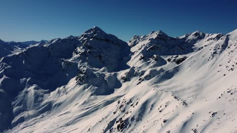 Winter-season-in-Alps-with-snow-covered-mountain-slopes,-aerial