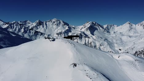 Gondola-ski-lift-on-mountain-top-in-winter-snow-alps,-aerial