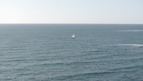 Aerial-static-of-a-sailboat-surrounded-by-the-Pacific-Ocean-and-blue-sky-on-a-sunny-day-in-San-Diego,-California