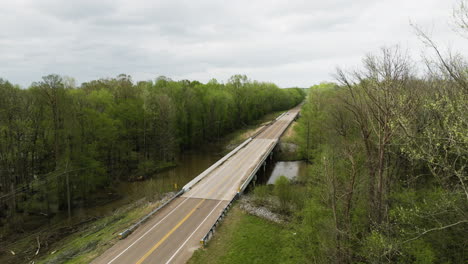 A-rural-road-crossing-a-river-amidst-green-forests-in-tennessee,-evoking-tranquility,-aerial-view