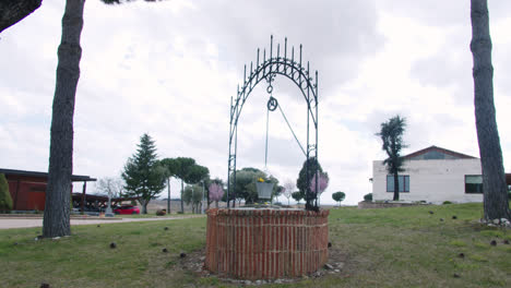 Wunderschöne-Zeitlupenaufnahme-Eines-Wasserbrunnens-Aus-Stein-Inmitten-Eines-Gartens-Vor-Einer-Weinfabrik-In-Burgos,-Spanien