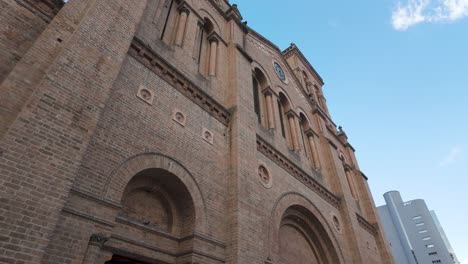 Flock-of-pigeons-soar-across-sky-in-front-of-brown-brick-Metropolitana-Cathedral-in-Medellin