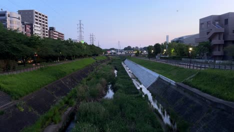 Die-Morgendämmerung-Bricht-über-Einem-Städtischen-Wasserkanal-An,-Der-Von-Grünflächen-Und-Wohngebäuden-Umgeben-Ist