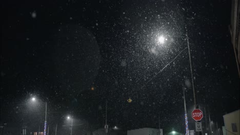 Winter-snowfall-at-night-snowing-on-city-street-in-street-light