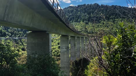 Concrete-bridge-high-above-the-trees-and-forest-floor-on-a-sunny-day,-New-Zealand-wide-shot