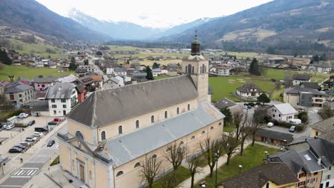 Large-light-brown-church-located-in-the-center-of-a-small-town-in-the-mountains-of-France
