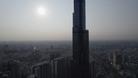 Landmark-81-tower-in-Ho-Chi-Minh-City,-Saigon,-the-highest-building-in-Vietnam-viewed-during-sunset,-aerial-ascending-drone-video