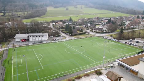 Kinder-Spielen-Ball-Auf-Einem-Fußballfeld-Am-Rande-Der-Stadt-Mit-Der-Feuerwehr-Im-Hintergrund