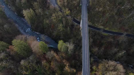 Leere-Brücke-In-Einem-Wald,-Die-An-Einem-Frühen-Frühlingstag-über-Ein-Felsiges-Flussufer-Mit-Klarem,-Blauem-Wasser-Führt