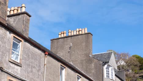 A-row-of-old-traditional-rooftop-chimneys-on-terraced-houses-in-Oban,-Western-Scotland-UK