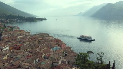 Erkunden-Sie-Die-Burg-Von-Malcesine-Mit-Blick-über-Die-Dächer-Der-Stadt,-Eine-Bootsfahrt-Auf-Dem-Gardasee,-Umgeben-Von-Nebligen-Bergen-Bei-Sonnenuntergang