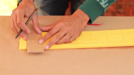 Artisan-drawing-lines-on-crepe-paper-and-cutting-it-with-scissors-for-decorations