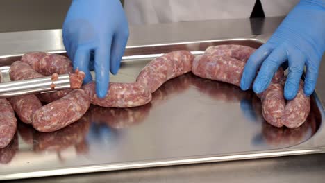 The-butcher-prepares-raw-sausage-for-baking-in-the-oven