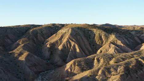 Las-Imágenes-Aéreas-Se-Retiran,-Revelando-Las-Tierras-Baldías,-áreas-Geológicas-Marcadas-Por-Formaciones-Rocosas-Fuertemente-Erosionadas.