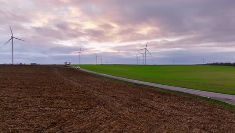 Plan-drone-road-crossing-and-wind-farm-in-France,-stormy-weather-late-afternoon-in-France
